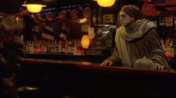 Movie still from “Mighty Aphrodite” (1995), directed by Woody Allen – A man sitting at the bar of a bar; Medium shot, Over the shoulder angle