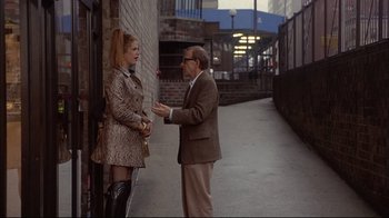 Movie still from “Mighty Aphrodite” (1995), directed by Woody Allen – A man and a woman standing next to each other on the sidewalk; Wide shot, Over the shoulder angle