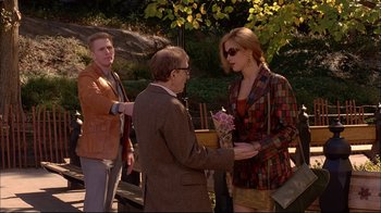 Movie still from “Mighty Aphrodite” (1995), directed by Woody Allen – A man and a woman exchanging a bouquet of flowers with another man; Medium shot, Over the shoulder angle