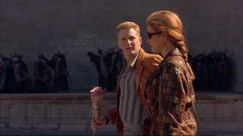 Movie still from “Mighty Aphrodite” (1995), directed by Woody Allen – A man and a woman standing next to each other holding flowers; Medium shot, Over the shoulder angle