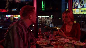 Movie still from “Mighty Aphrodite” (1995), directed by Woody Allen – A man and a woman sitting at a table with plates of food in front of them; Medium shot, Over the shoulder angle