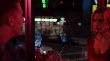 Movie still from “Mighty Aphrodite” (1995), directed by Woody Allen – A view of a city from a restaurant window at night time; Medium shot, Over the shoulder angle
