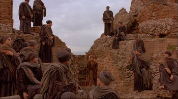 Movie still from “Mighty Aphrodite” (1995), directed by Woody Allen – A group of men standing on top of a brick wall; Wide shot, Low angle