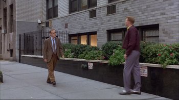 Movie still from “Mighty Aphrodite” (1995), directed by Woody Allen – Two men walking down the sidewalk in front of a building; Wide shot, Low angle