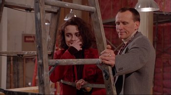 Movie still from “Mighty Aphrodite” (1995), directed by Woody Allen – A man and a woman standing next to a wooden ladder; Medium shot, Low angle
