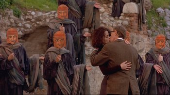 Movie still from “Mighty Aphrodite” (1995), directed by Woody Allen – A man and a woman kissing in front of a group of people; Medium shot, Over the shoulder angle
