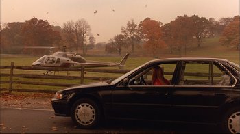 Movie still from “Mighty Aphrodite” (1995), directed by Woody Allen – A woman sitting in the driver's seat of a black car; Extreme Wide shot, Low angle
