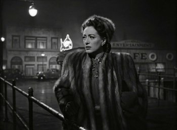Movie still from “Mildred Pierce” (1945), directed by Michael Curtiz – An old photo of a woman wearing a fur coat; Medium shot, Low angle