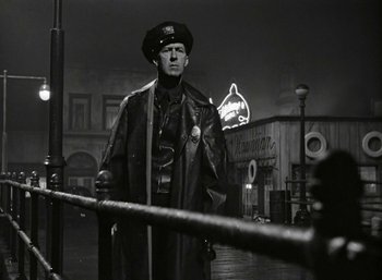 Movie still from “Mildred Pierce” (1945), directed by Michael Curtiz – A man wearing a hat standing next to a railing; Medium shot, Low angle