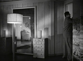 Movie still from “Mildred Pierce” (1945), directed by Michael Curtiz – A man standing next to a door in a room; Wide shot, Low angle