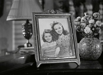 Movie still from “Mildred Pierce” (1945), directed by Michael Curtiz – An old photo of two young girls sitting on a table; Close Up shot, High angle