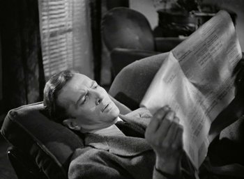 Movie still from “Mildred Pierce” (1945), directed by Michael Curtiz – A black and white photo of a man reading a newspaper; Close Up shot, High angle