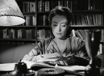 Movie still from “Mildred Pierce” (1945), directed by Michael Curtiz – A black and white photo of a woman sitting at a table; Medium shot, High angle