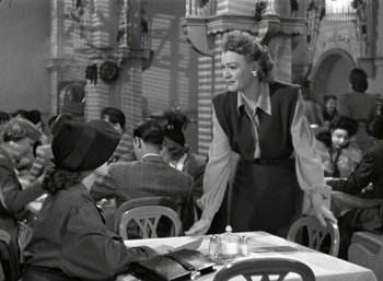 Movie still from “Mildred Pierce” (1945), directed by Michael Curtiz – An old photo of two people sitting at a table; Medium shot, Over the shoulder angle