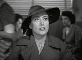 Movie still from “Mildred Pierce” (1945), directed by Michael Curtiz – A woman wearing a hat and a trench coat; Close Up shot, Over the shoulder angle