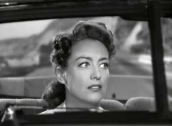 Movie still from “Mildred Pierce” (1945), directed by Michael Curtiz – A black and white photo of a woman looking out a car window; Close Up shot, High angle