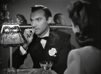 Movie still from “Mildred Pierce” (1945), directed by Michael Curtiz – A black and white photo of a man smoking a cigarette; Close Up shot, Over the shoulder angle