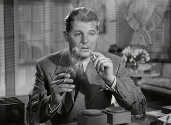 Movie still from “Mildred Pierce” (1945), directed by Michael Curtiz – A black and white photo of a man smoking a cigarette; Medium shot, Low angle