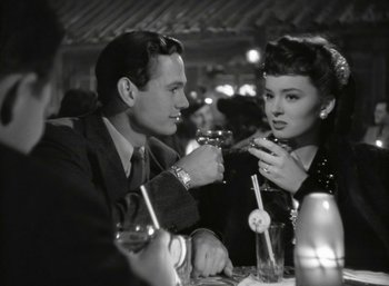 Movie still from “Mildred Pierce” (1945), directed by Michael Curtiz – A man and a woman sitting at a dinner table; Medium shot, Low angle