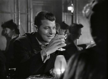 Movie still from “Mildred Pierce” (1945), directed by Michael Curtiz – A black and white photo of a man drinking a glass of wine; Close Up shot, Over the shoulder angle