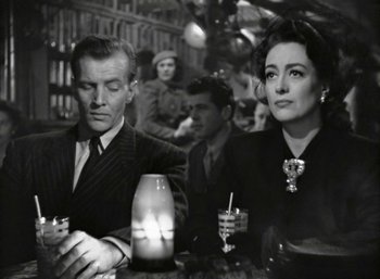 Movie still from “Mildred Pierce” (1945), directed by Michael Curtiz – A man and a woman sitting at a table with a candle; Medium shot, High angle