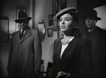Movie still from “Mildred Pierce” (1945), directed by Michael Curtiz – A black and white photo of a woman in a suit and hat; Medium shot, Over the shoulder angle