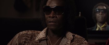 Movie still from “Miles Ahead” (2015), directed by Don Cheadle – A man wearing sunglasses sitting in front of a window; Close Up shot, Low angle