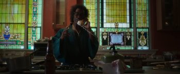 Movie still from “Miles Ahead” (2015), directed by Don Cheadle – A man talking on a phone in front of stained glass windows; Medium shot, Low angle