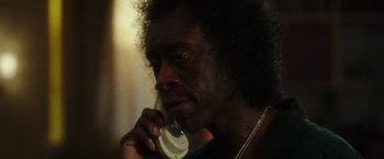 Movie still from “Miles Ahead” (2015), directed by Don Cheadle – A man talking on a cell phone while wearing a necklace; Close Up shot, Low angle