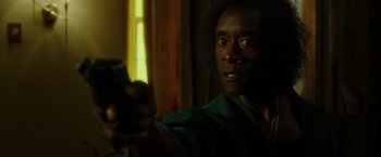 Movie still from “Miles Ahead” (2015), directed by Don Cheadle – A man holding a gun in a room with yellow curtains; Close Up shot, Low angle