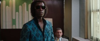 Movie still from “Miles Ahead” (2015), directed by Don Cheadle – A man in a blue shirt and a man in a suit and tie; Medium shot, Low angle