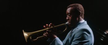 Movie still from “Miles Ahead” (2015), directed by Don Cheadle – A man in a blue suit playing a trumpet; Close Up shot, Low angle