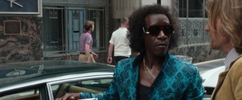 Movie still from “Miles Ahead” (2015), directed by Don Cheadle – A man in a blue jacket is standing in front of a car; Close Up shot, Over the shoulder angle