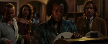 Movie still from “Miles Ahead” (2015), directed by Don Cheadle – A man in a blue and black jacket is looking down at an object; Close Up shot, Low angle
