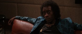 Movie still from “Miles Ahead” (2015), directed by Don Cheadle – A man sitting on top of a couch wearing a blue jacket; Close Up shot, Low angle