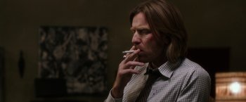 Movie still from “Miles Ahead” (2015), directed by Don Cheadle – A man smoking a cigarette while wearing a shirt and tie; Close Up shot, Over the shoulder angle