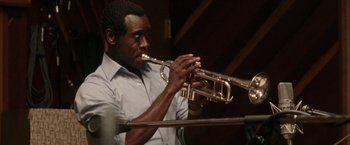 Movie still from “Miles Ahead” (2015), directed by Don Cheadle – A man playing the trumpet in a room; Close Up shot, Low angle