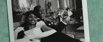 Movie still from “Miles Ahead” (2015), directed by Don Cheadle – A man and a woman sitting next to each other holding a trophy; Medium shot, Low angle