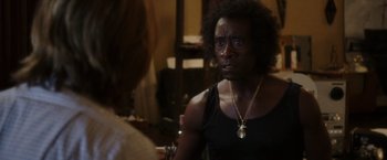 Movie still from “Miles Ahead” (2015), directed by Don Cheadle – A person with a necklace is looking at the camera; Close Up shot, Over the shoulder angle