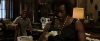 Movie still from “Miles Ahead” (2015), directed by Don Cheadle – A woman is holding a banana in her hand; Medium shot, Over the shoulder angle
