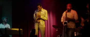 Movie still from “Miles Ahead” (2015), directed by Don Cheadle – A man playing a trumpet on a stage; Medium shot, Low angle