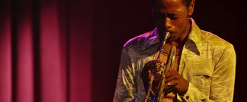 Movie still from “Miles Ahead” (2015), directed by Don Cheadle – A man playing a trumpet on a stage; Close Up shot, Low angle