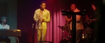 Movie still from “Miles Ahead” (2015), directed by Don Cheadle – A man standing on a stage playing a saxophone; Medium shot, Low angle