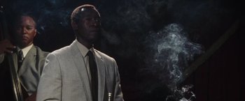 Movie still from “Miles Ahead” (2015), directed by Don Cheadle – A man in a suit and tie standing in front of smoke; Close Up shot, Low angle