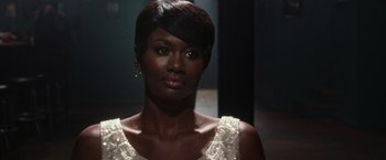 Movie still from “Miles Ahead” (2015), directed by Don Cheadle – A woman in a white dress is posing for a picture; Close Up shot, Over the shoulder angle