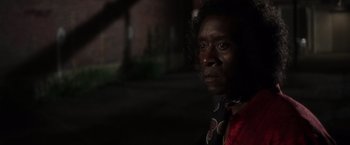 Movie still from “Miles Ahead” (2015), directed by Don Cheadle – A black woman with curly black hair wearing a red shirt and a black neck tie; Close Up shot, Over the shoulder angle
