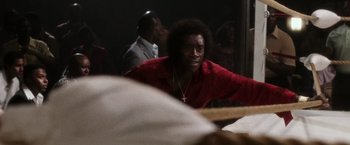 Movie still from “Miles Ahead” (2015), directed by Don Cheadle – A man sitting at a table in front of other people; Close Up shot, Over the shoulder angle