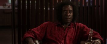 Movie still from “Miles Ahead” (2015), directed by Don Cheadle – A man in a red shirt is sitting in a chair; Close Up shot, Low angle