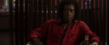 Movie still from “Miles Ahead” (2015), directed by Don Cheadle – A person sitting in a chair wearing a red shirt; Close Up shot, Low angle