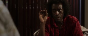 Movie still from “Miles Ahead” (2015), directed by Don Cheadle – A man in a red shirt is holding his hand up; Close Up shot, Over the shoulder angle